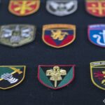 На фото — фрагмент виставки колекції нарукавних знаків американського добровольця Стіва Андре, представленої у Національний військово-історичний музей України. На стендах розміщені десятки шевронів і патчів різних підрозділів, акуратно згрупованих та закріплених на камуфльованому тлі.