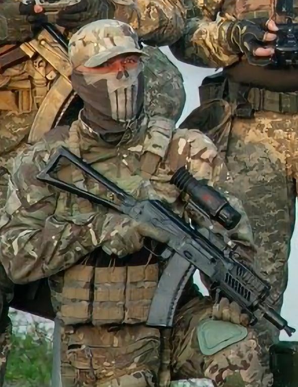 Захисник України у військовій формі та балаклаві з принтом черепа тримає зброю.