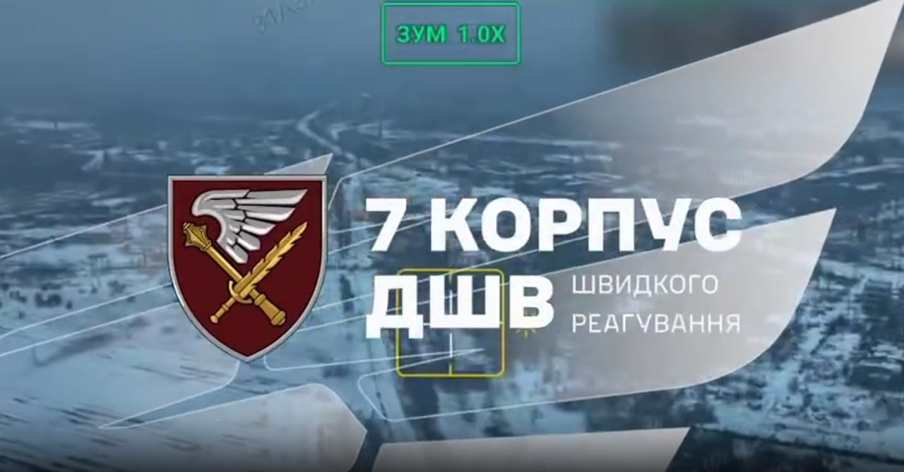 Графічне зображення з емблемою Десантно-штурмових військ України (маруновий щит із золотим мечем, крилами та булавою). Праворуч від емблеми великий білий напис: «7 КОРПУС ДШВ ШВИДКОГО РЕАГУВАННЯ». Тло зображення — розмитий засніжений краєвид міста або промислової зони, знятий з висоти (імовірно, з дрона), з накладеними елементами інтерфейсу: рамкою прицілювання та написом «ЗУМ 1.0Х» зверху.