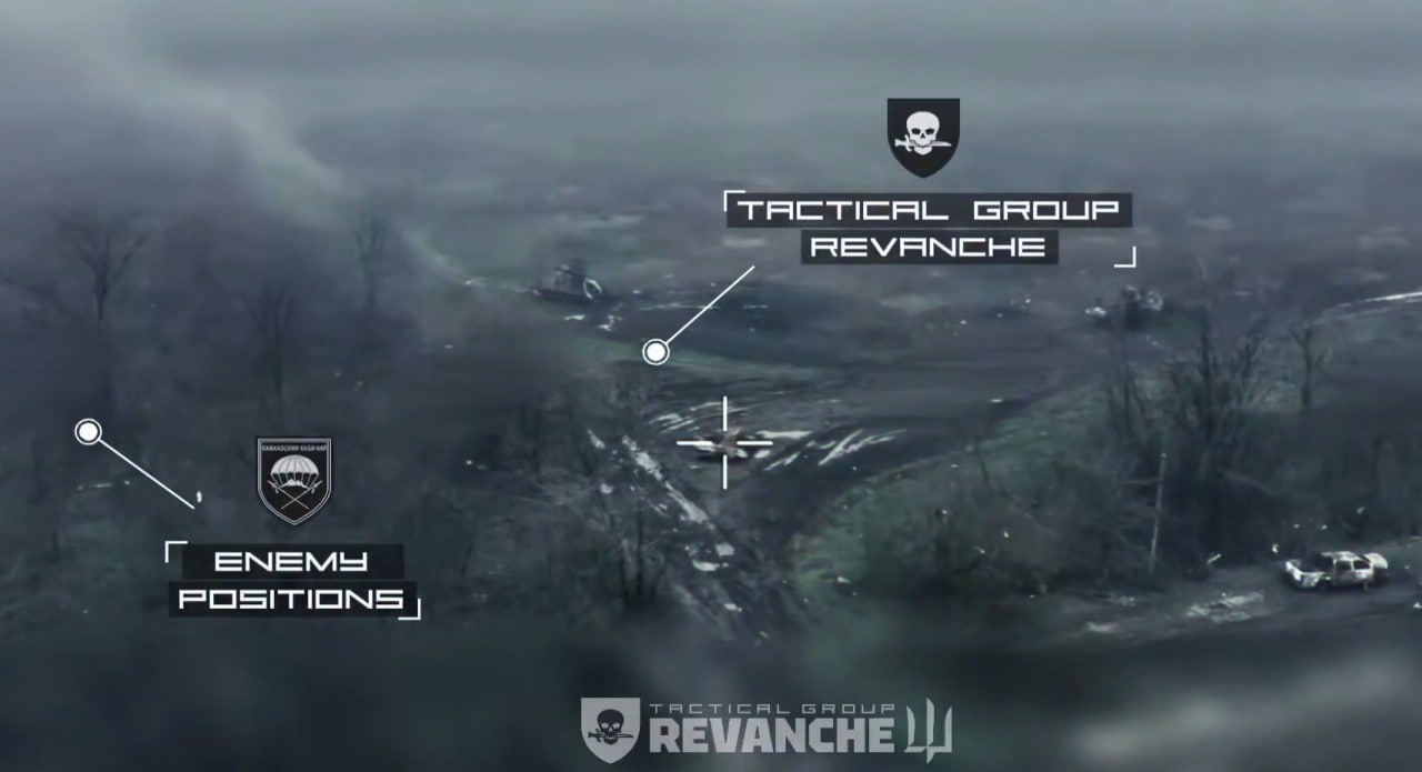 Зображення з камери розвідувального дрона над полем бою у сірих та похмурих тонах. На задимленій та понівеченій вибухами місцевості видно залишки ворожої техніки та позицій. На зображення накладено тактичну графіку: праворуч — напис «TACTICAL GROUP REVANCHE» з емблемою (череп із ножем у зубах), ліворуч — позначка «ENEMY POSITIONS» над ворожим об’єктом. У центрі екрана — біле перехрестя прицілу. Внизу — повний логотип підрозділу «Реванш» із тризубом.