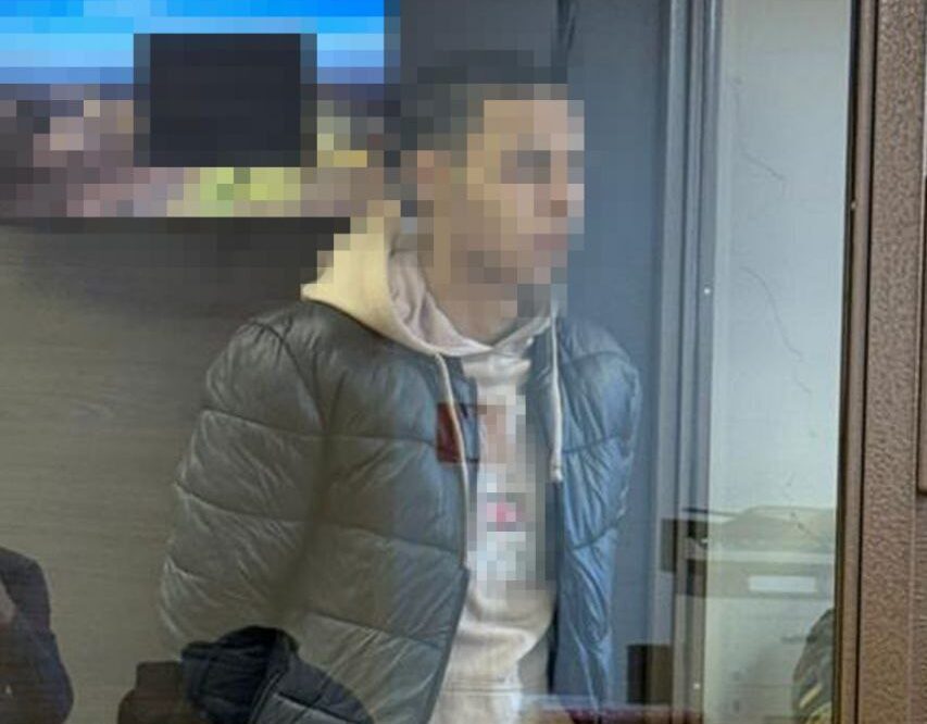 Чоловік, якого звинуватили у роботі на ворога, за скляною стіною у судовій залі