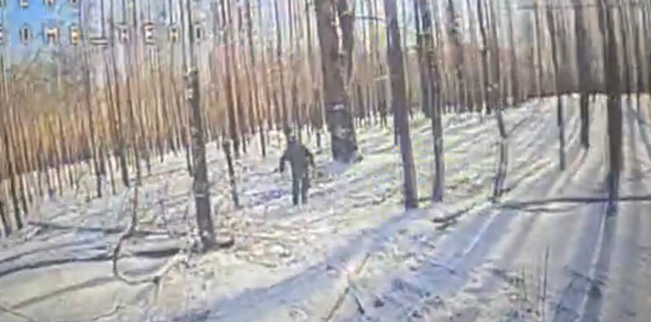 Окупант тікає від дрону по снігу у лісі.