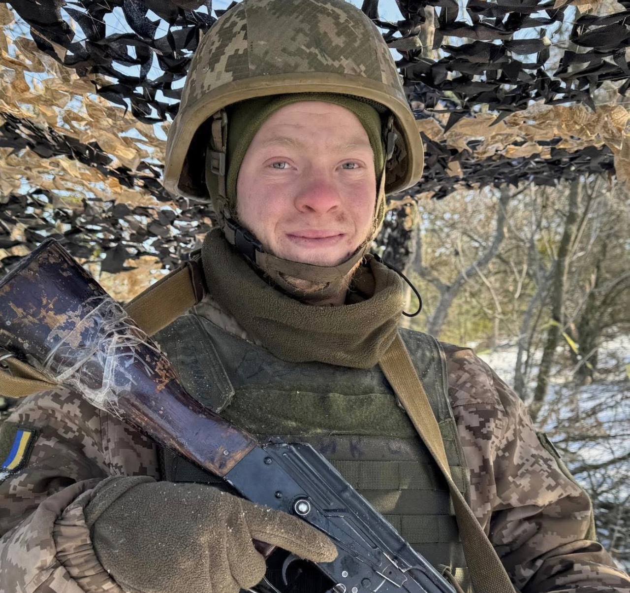 Боєць Сил оборони у бронежилеті, шоломі та з автоматом у руках.