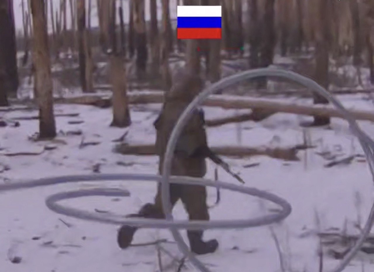 Окупант тікає від українського дрону з автоматом в руках через зимовий ліс.