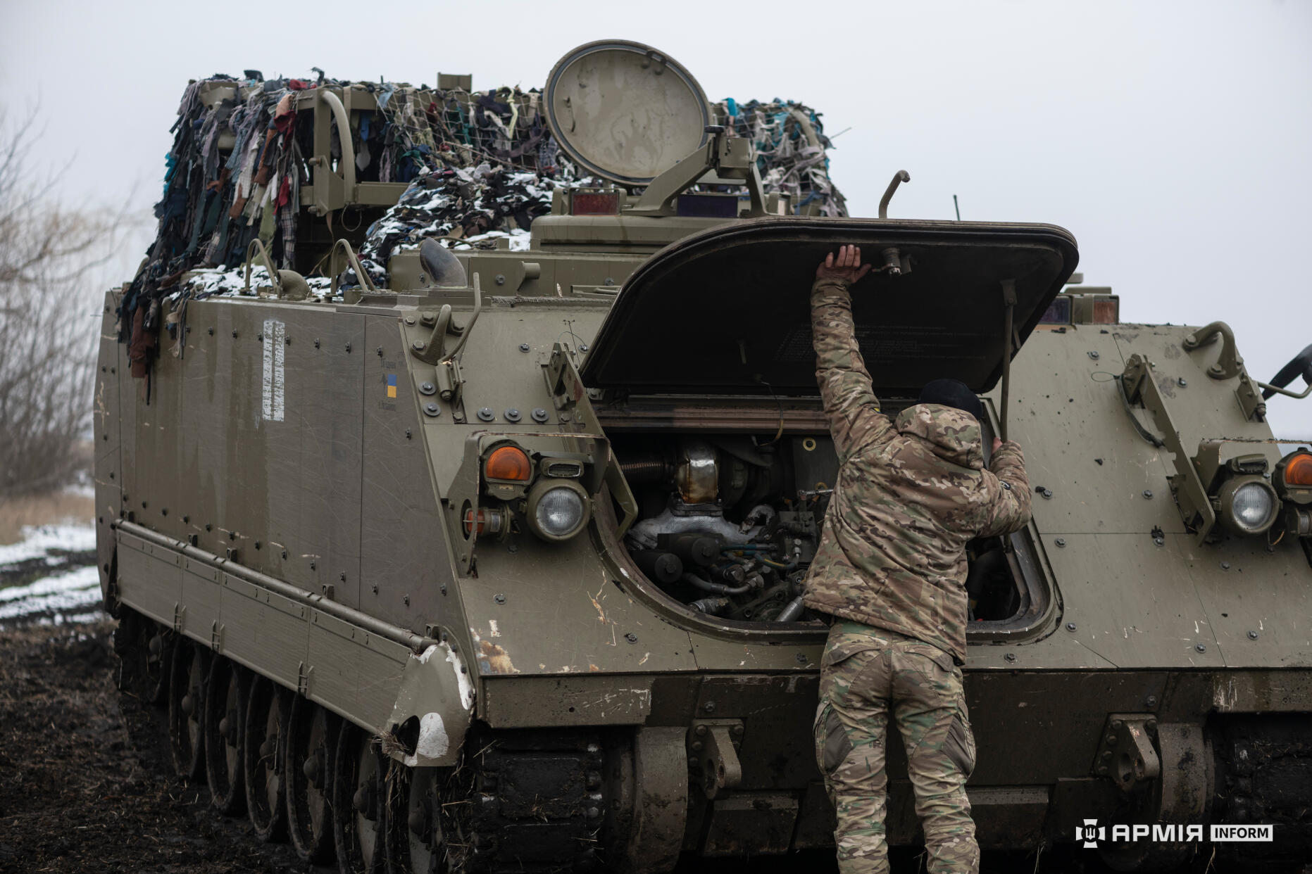 Боєць ЗСУ ремонтує броневик М-113