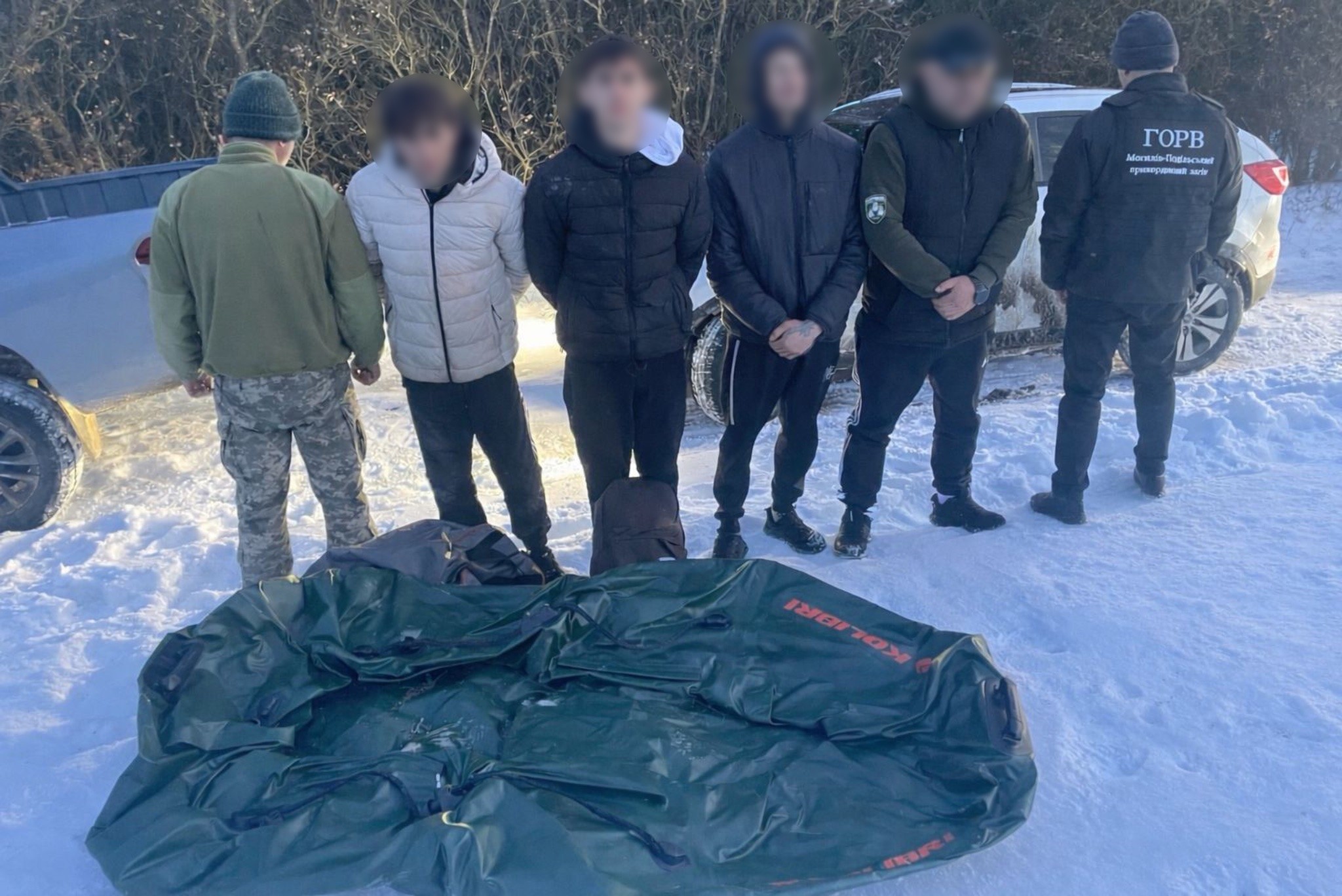 Затримані в оточенні прикордонників стоять перед човном