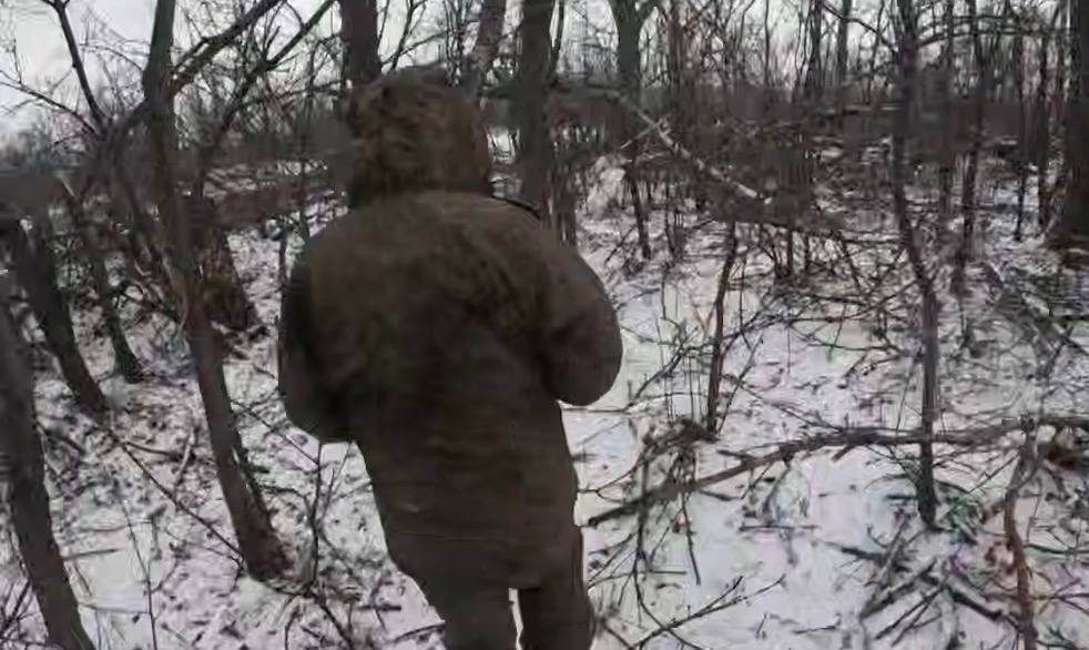 Полонений окупант під супроводом наших бійців йде засніженою посадкою.