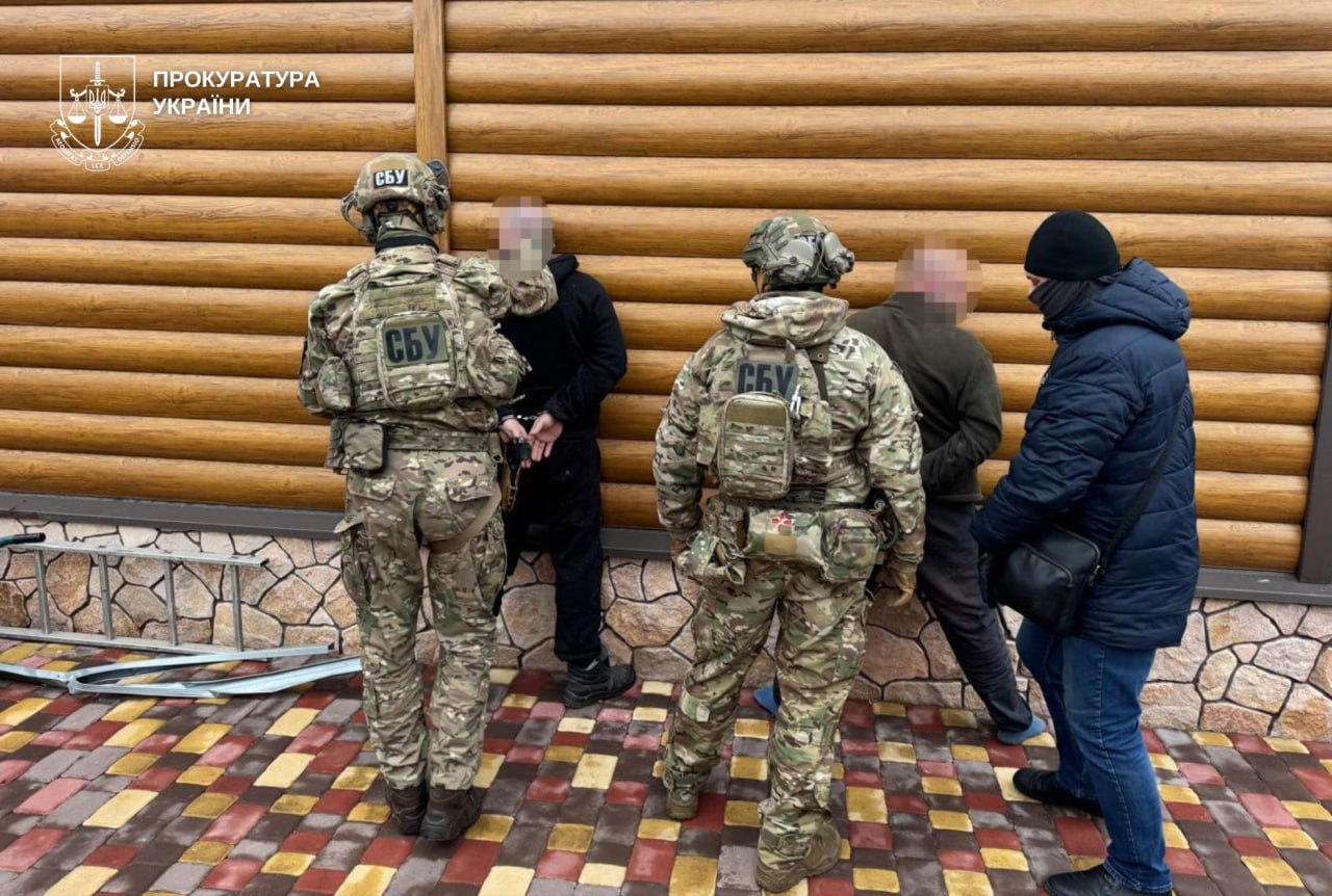 Затримані стоять обличчям до стіни в оточенні спецпризначенців