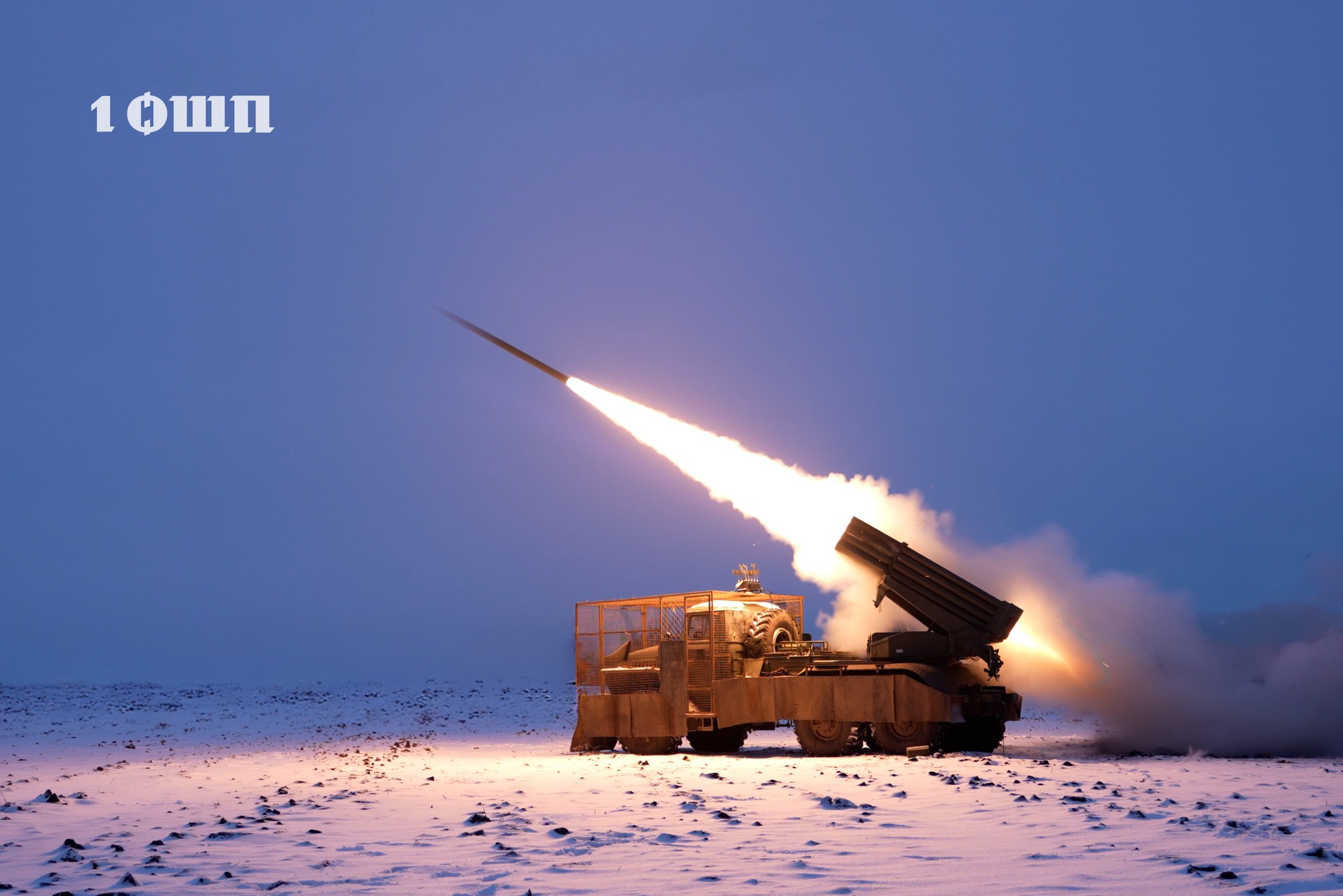 Реактивна система залпового вогню на засніженому полі здійснює пуск ракети, яскраве полум’я та шлейф диму розрізають сутінкове небо. Бойова машина прикрита захисними екранами, а навколо видно холодний зимовий ландшафт без укриттів.