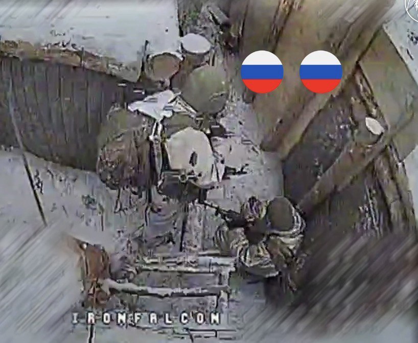 Двоє окупантів в окопі в бронежилетах і касках зі зброєю в руках за мить до ураження FPV-дроном