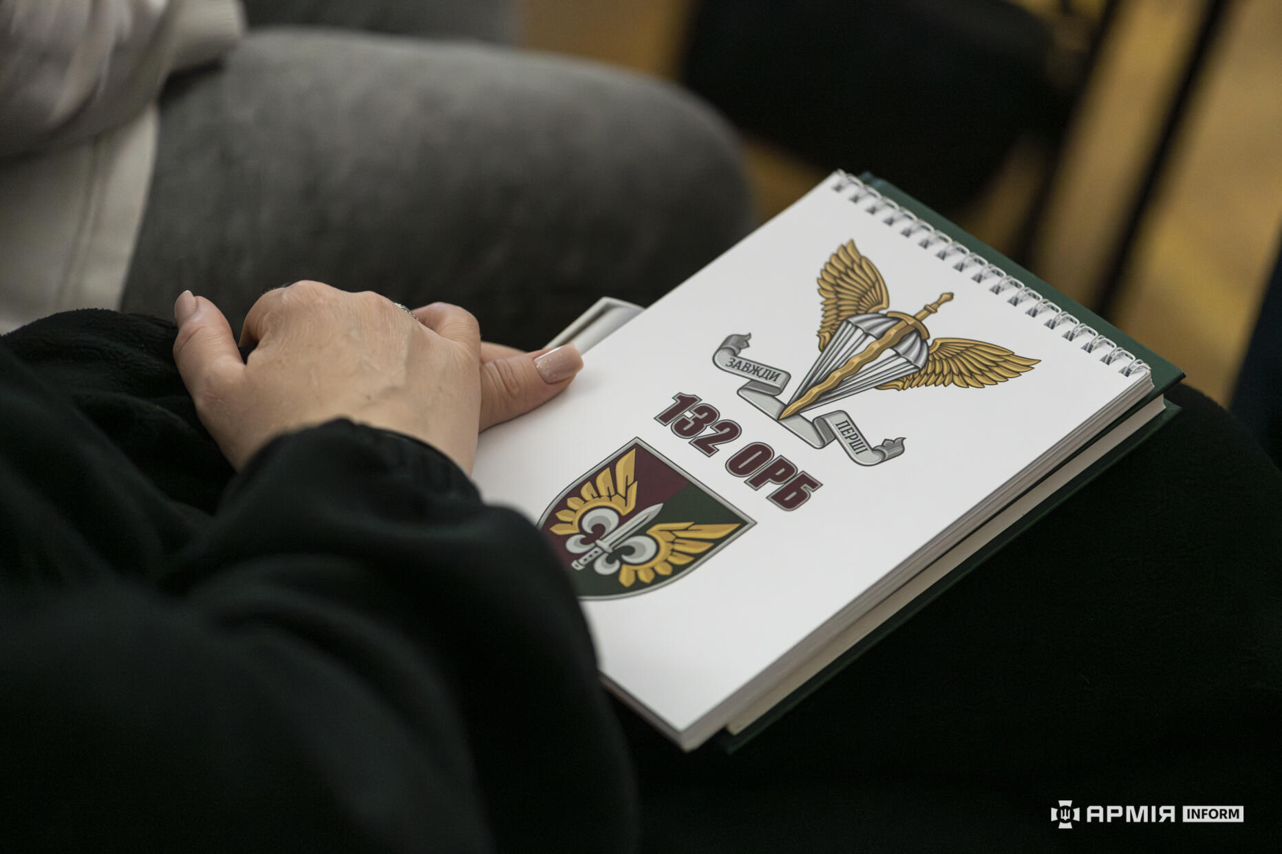 У руках однієї з учасниць видно блокнот із символікою 132 окремого розвідувального батальйону. Вона тримає його на колінах під час заходу, готуючись робити записи.