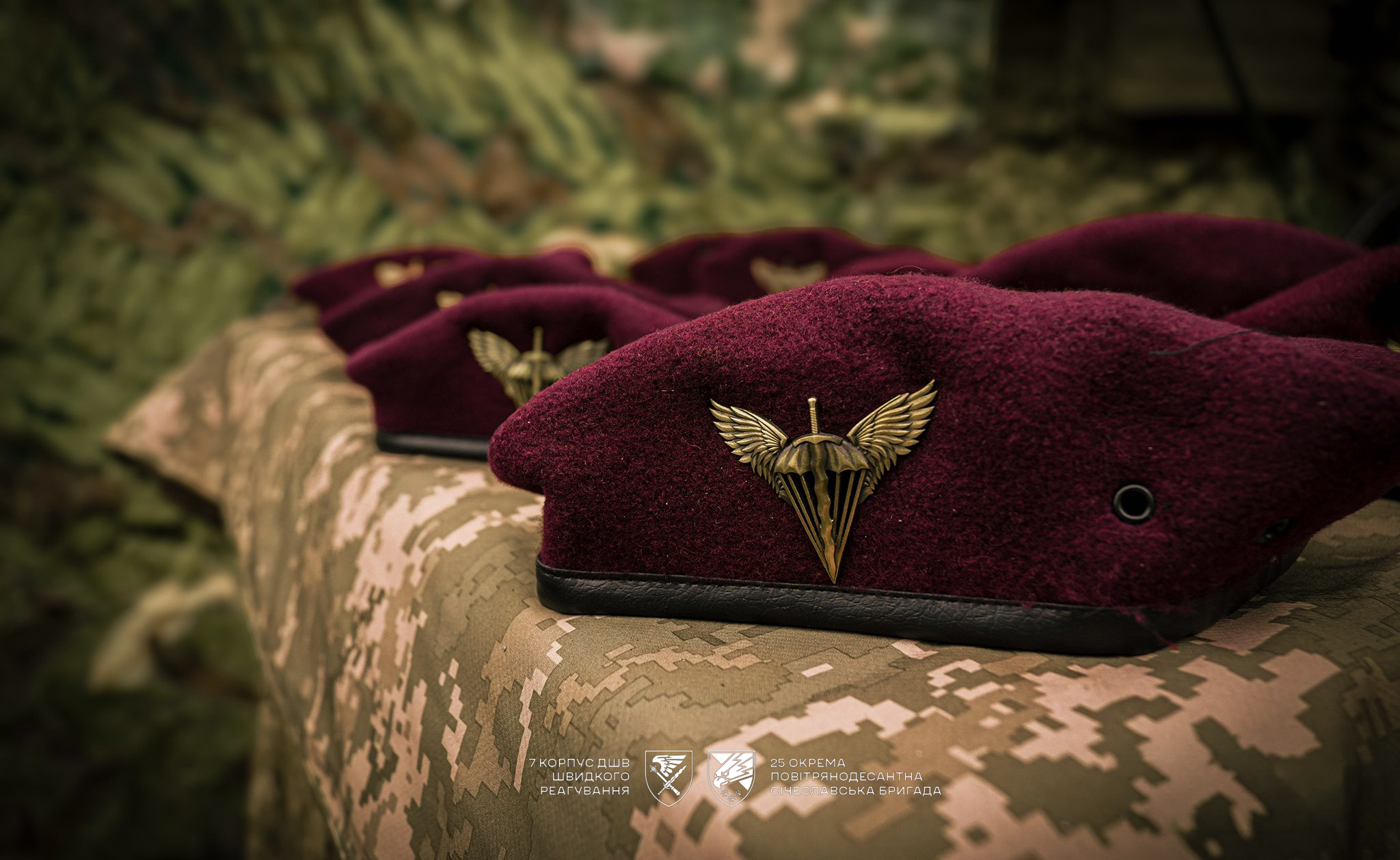 Бордові десантні берети з емблемами акуратно викладені на камуфльованій тканині. Фокус на символіці підкреслює належність до десантно-штурмових військ.