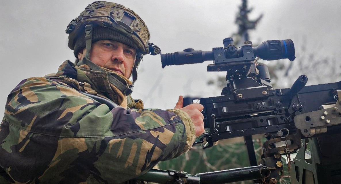 Боєць ЗСУ в шоломі та бронежилеті біля великокаліберного кулемету з прицілом для збиття повітряних цілей.