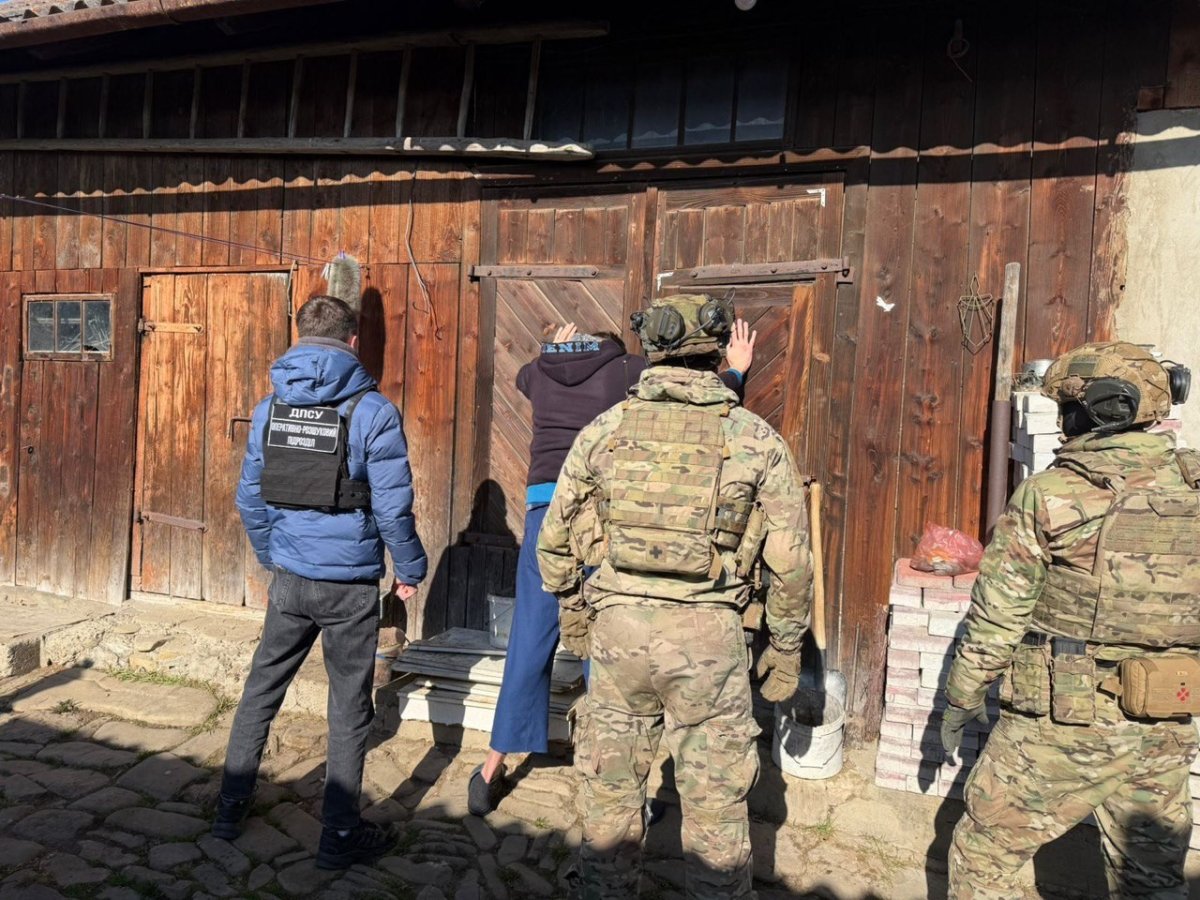 Затриманий чоловік стоїть обличчям до стіни.