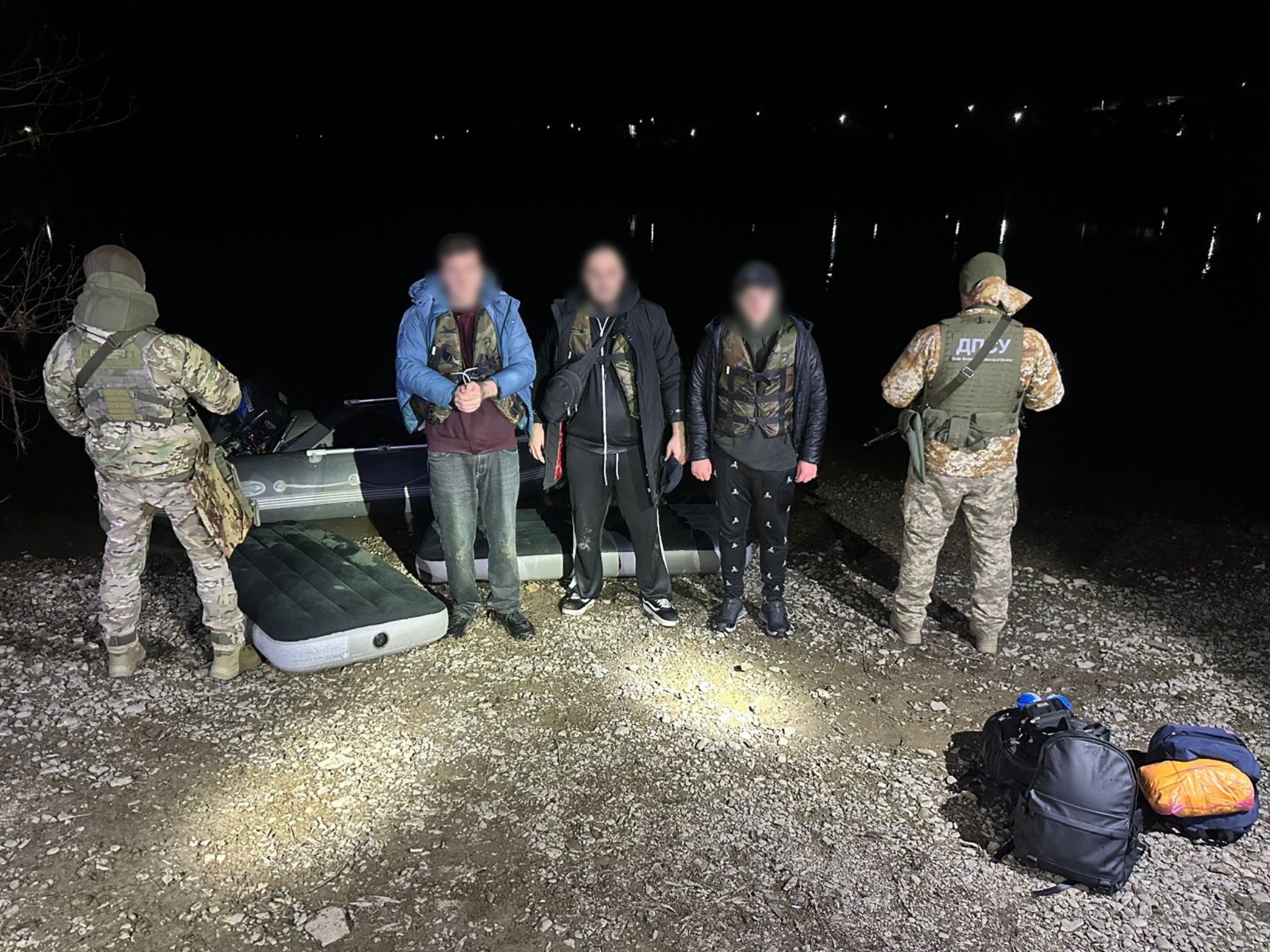 Затримані в оточенні прикордонників стоять на березі Дністра