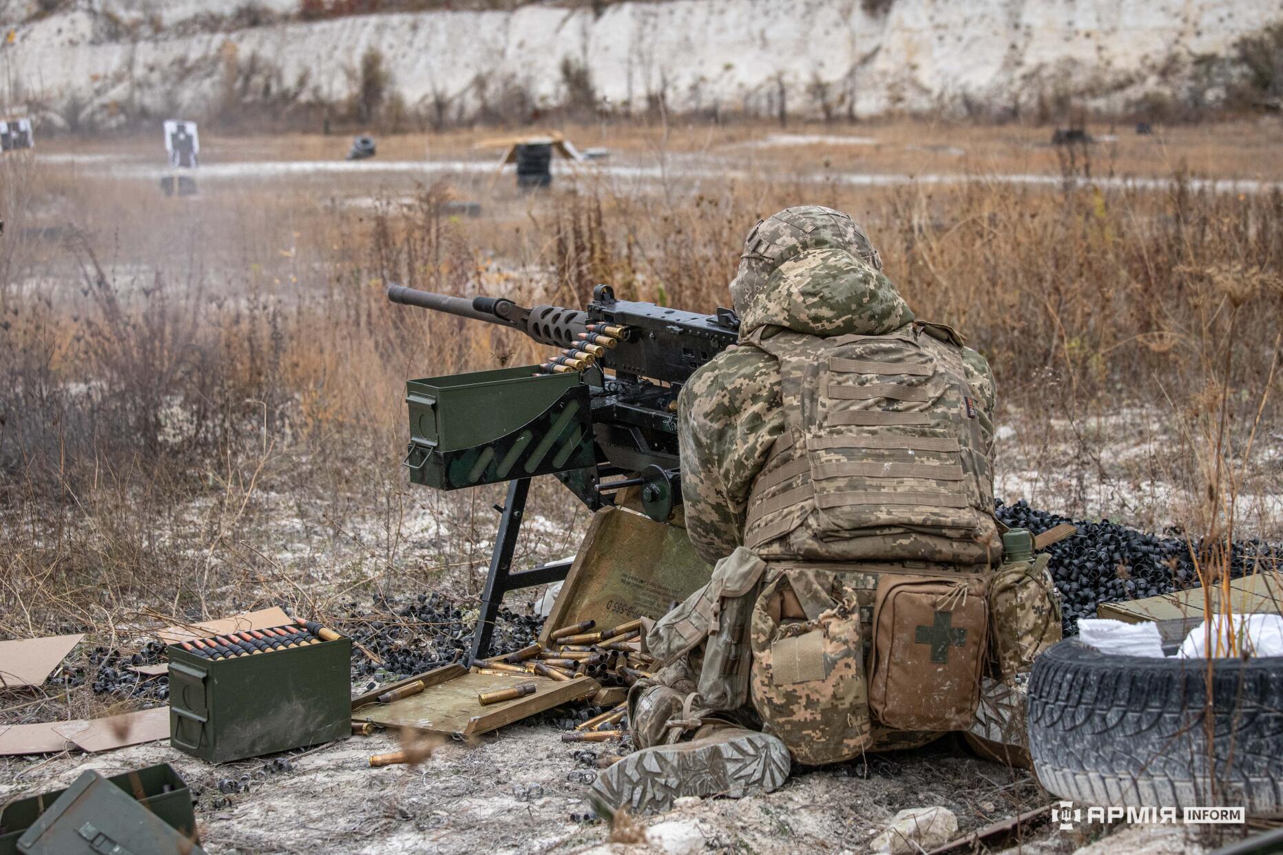 Боєць ЗСУ веде вогонь з кулемета на навчальному полігоні