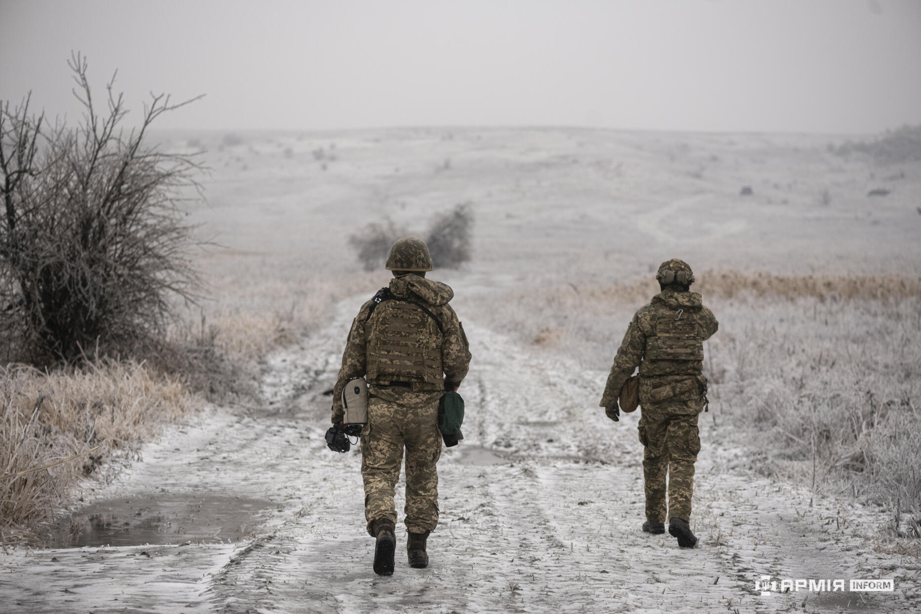 Двоє бійців ЗСУ йдуть засніженою дорогою через поле