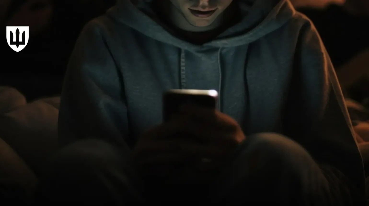 Людина у темряві дивиться на екран смартфона