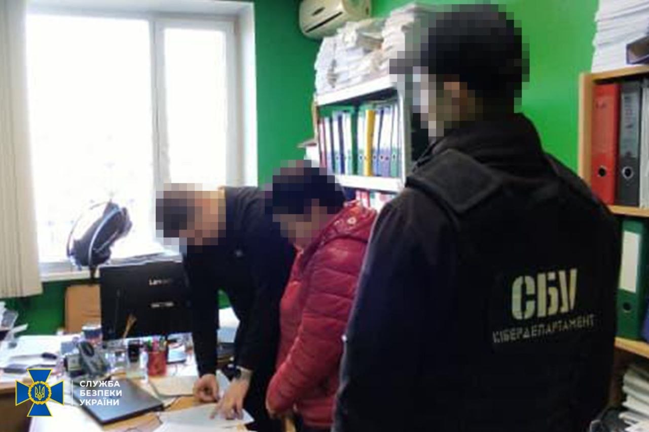 Жінка в оточенні двох правоохоронців стоїть біля столу