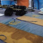 На столі розміщені історичні синьо-жовті прапорці з тризубами, поряд із сурмою та архівними документами. Експозиція поєднує військову символіку та предмети доби Української Народної Республіки.