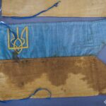 Один із прапорців показано детально, що дозволяє роздивитися тканину, кольори та символіку тризуба. Видно сліди часу, які підкреслюють автентичність експоната.