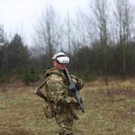 Боєць у віртуальному шоломі зупинився, зосереджено орієнтуючись у симульованому середовищі. Його спорядження та поза свідчать про відпрацювання тактичних дій.