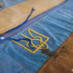 На фото крупним планом показано фрагменти історичних синьо-жовтих прапорів із вишитими тризубами. Експонати демонструють символіку української державності та військової традиції періоду визвольних змагань.