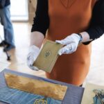 На фото кураторка тримає невеликий документ із символікою Української Народної Республіки. Це, ймовірно, історичний паспорт або посвідчення, пов’язане з державними структурами УНР.