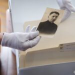 На знімку показано старовинний портрет, який обережно тримають під час роботи з архівною колекцією. Фото ілюструє процес збереження та вивчення персональних історичних матеріалів.