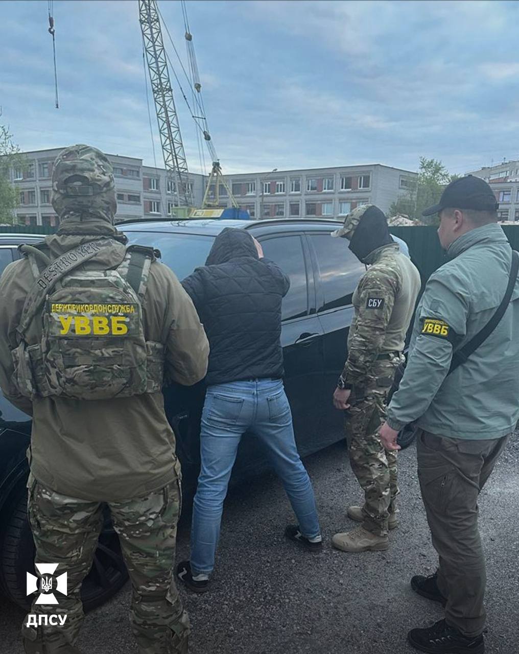 Затриманий стоїть поклавши руки на дах свого авто. Навколо правоохоронці