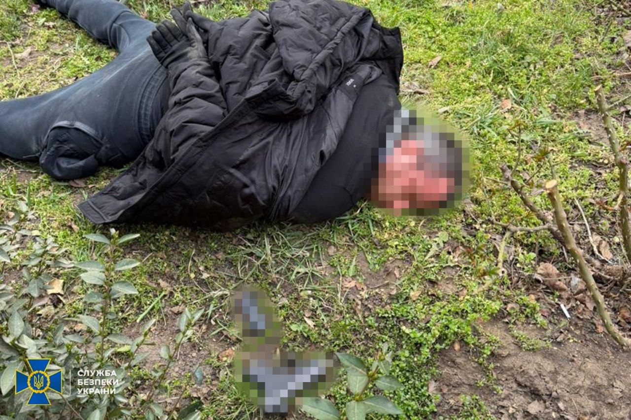 Затриманий лежить на землі поряд зі своїм пістолетом