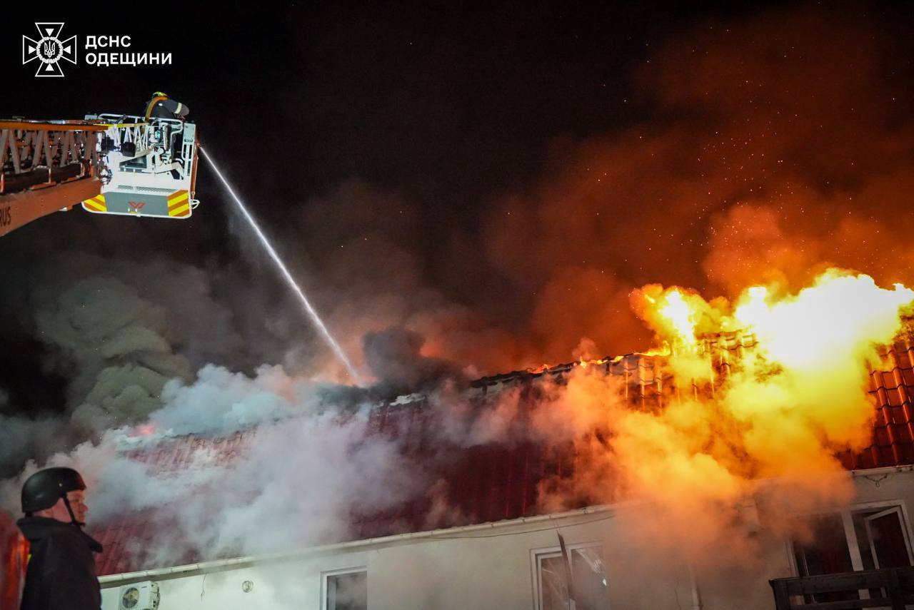Рятувальники ДСНС гасять вогонь на даху пошкодженої будівлі.