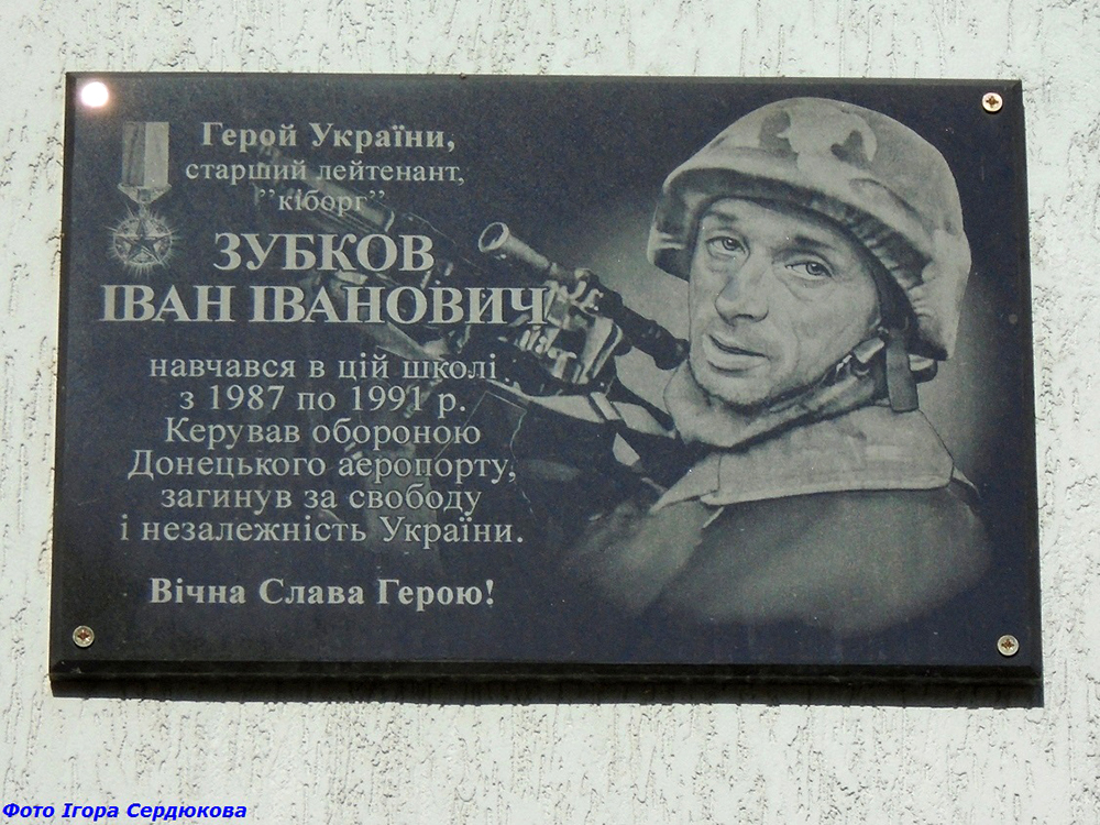 Меморіальна дошка вшановує Героя України Івана Зубкова, одного з оборонців Донецького аеропорту. На плиті розміщено його портрет, військові символи та текст про бойовий шлях і загибель.