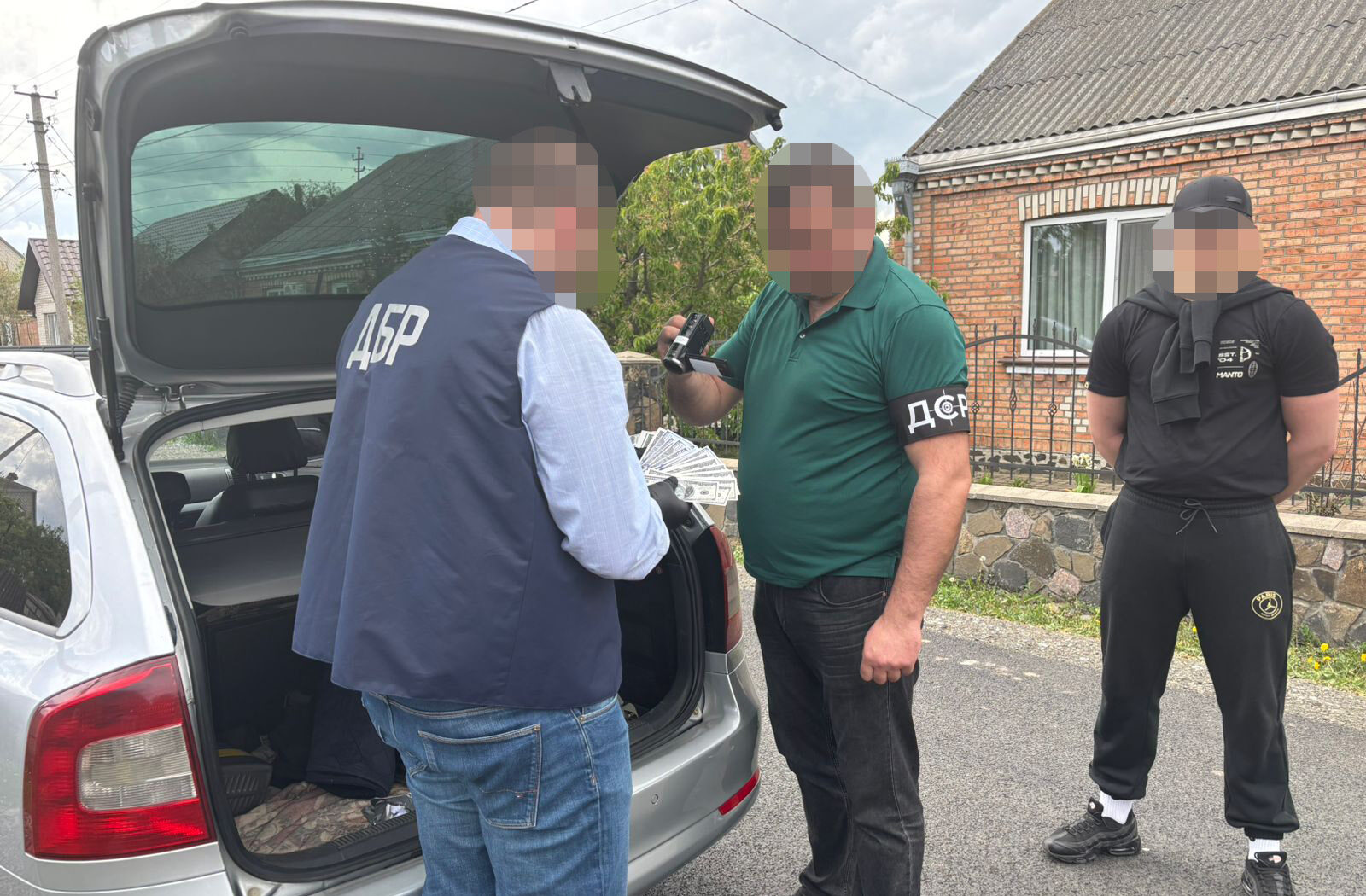 Правоохоронці біля відкритого багажника авто рахують гроші