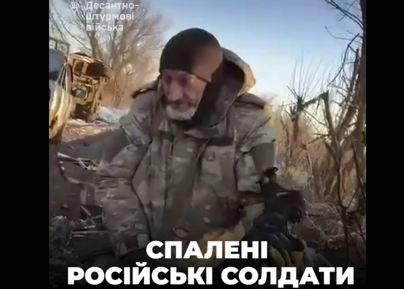 Ворожий солдат несе обгорілі рештки колеги