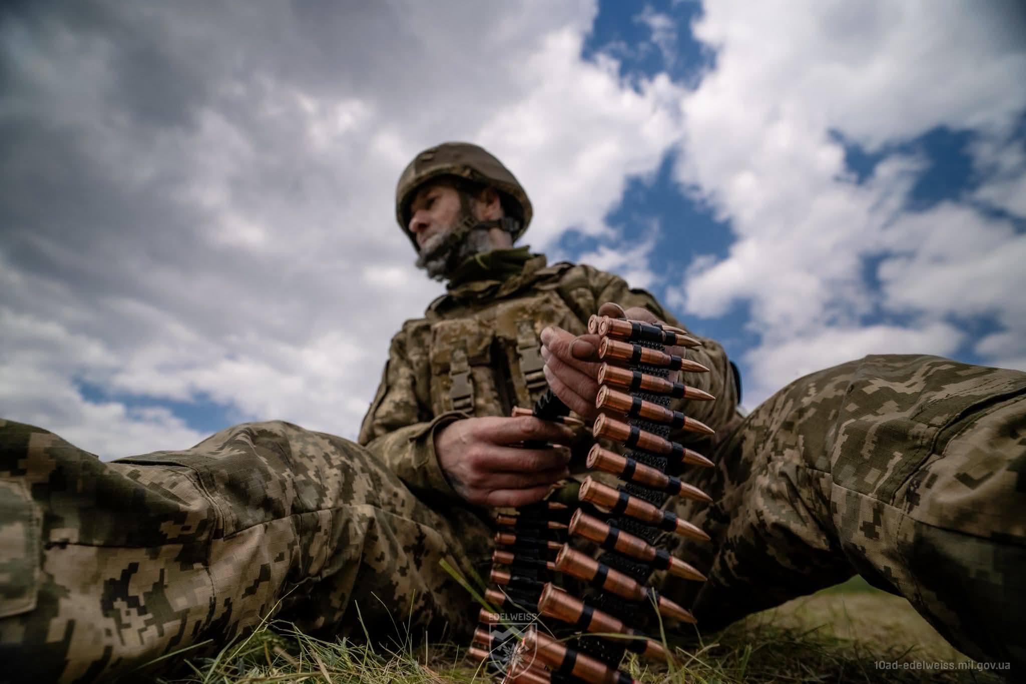 Наш воїн сидить і тримає ленту з набоями