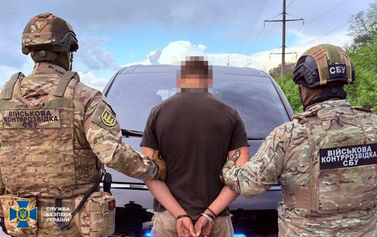 Двоє співробітників СБУ тримають затриманого у кайданках