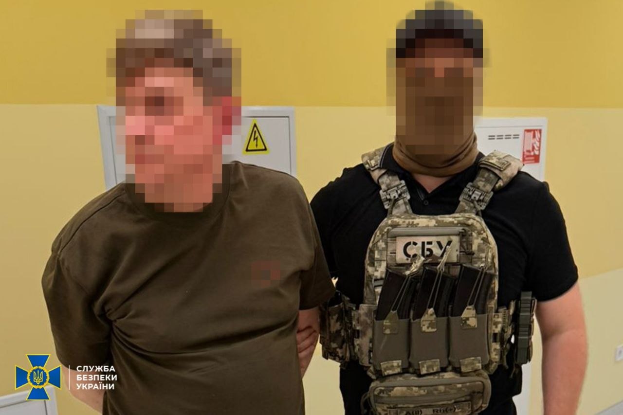 Затриманий стоїть поруч з правоохоронцем