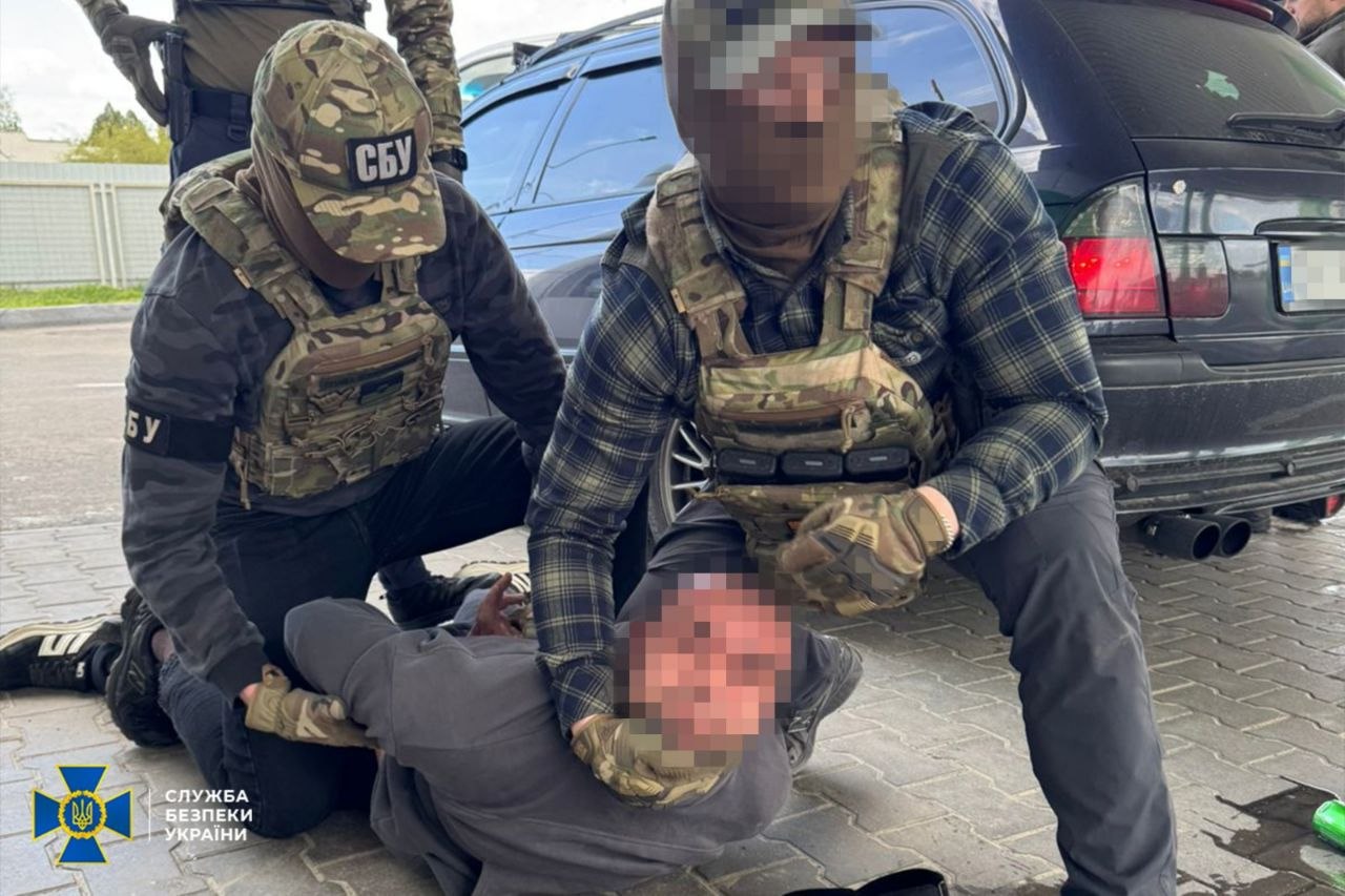 Затриманий ділок лежить на землі, а над ним присіли двоє правоохоронців
