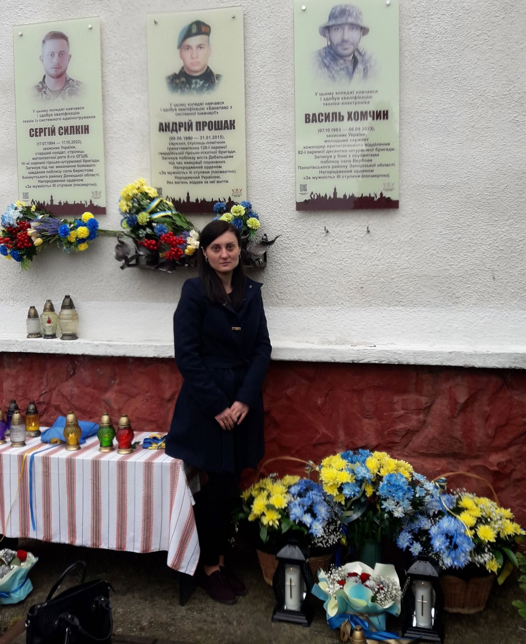 Дружина Василя Хомчина біля меморіальної таблички на його честь