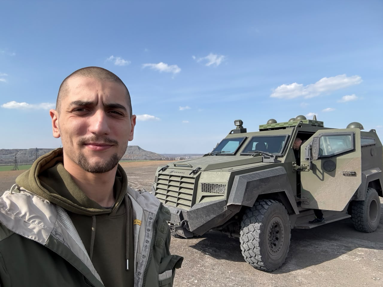 Боєць стоїть на фоні броньовика.