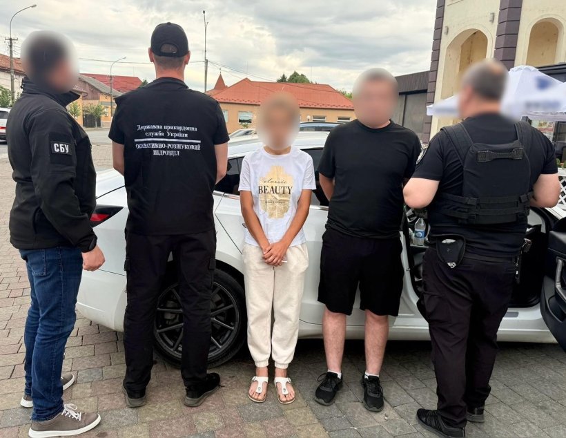 Затримані в оточенні правоохоронців стоять біля авто