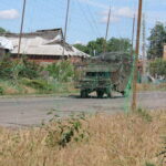 Військовий автомобіль їде на велосипеді по дорозі, вкритій протидроновою сіткою