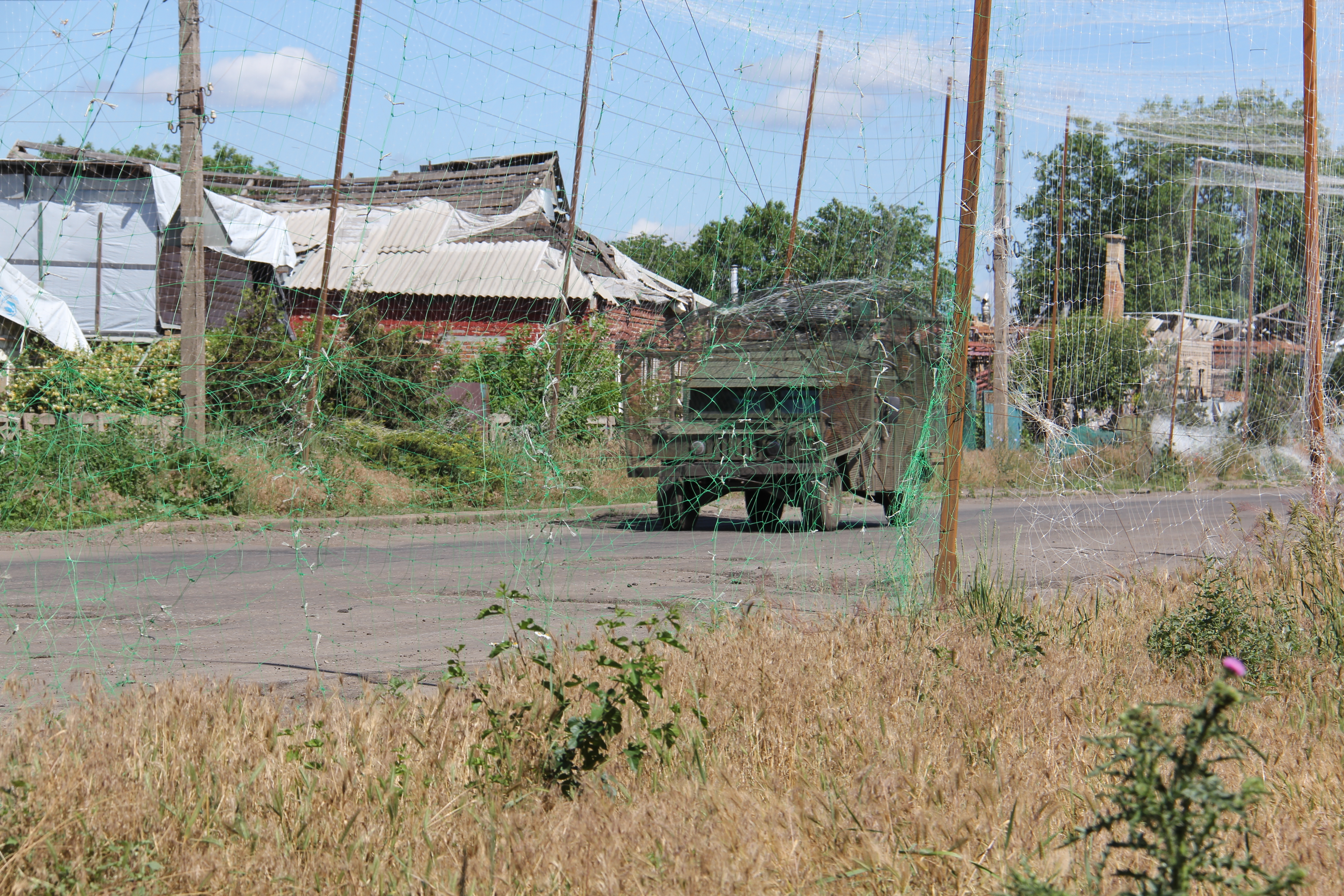 Військовий автомобіль їде на велосипеді по дорозі, вкритій протидроновою сіткою
