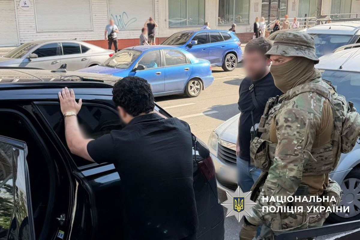 Затриманий стоїть обличчям до своєї машини