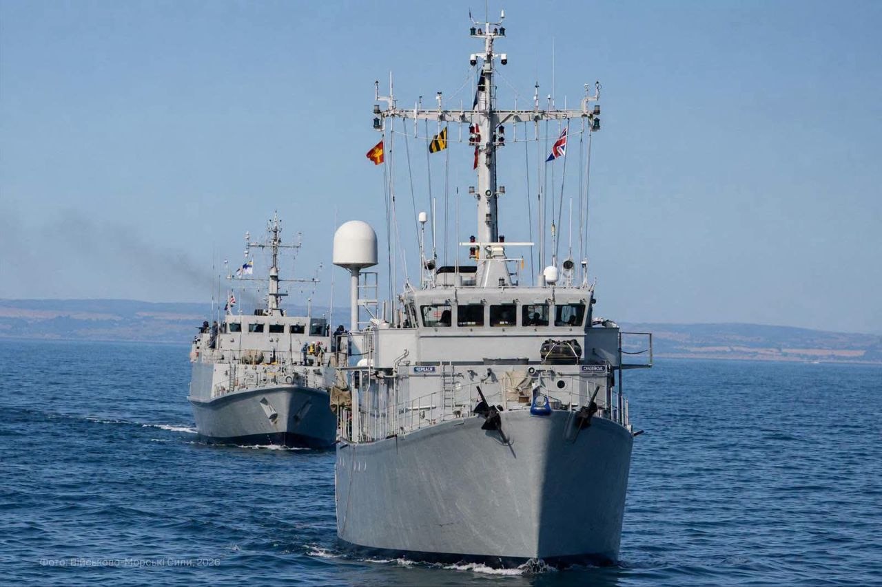 Два протимінні кораблі рухаються морем один за одним у кільватерному строю. На щоглах переднього судна піднято прапори кількох держав — учасниць спільних навчань.