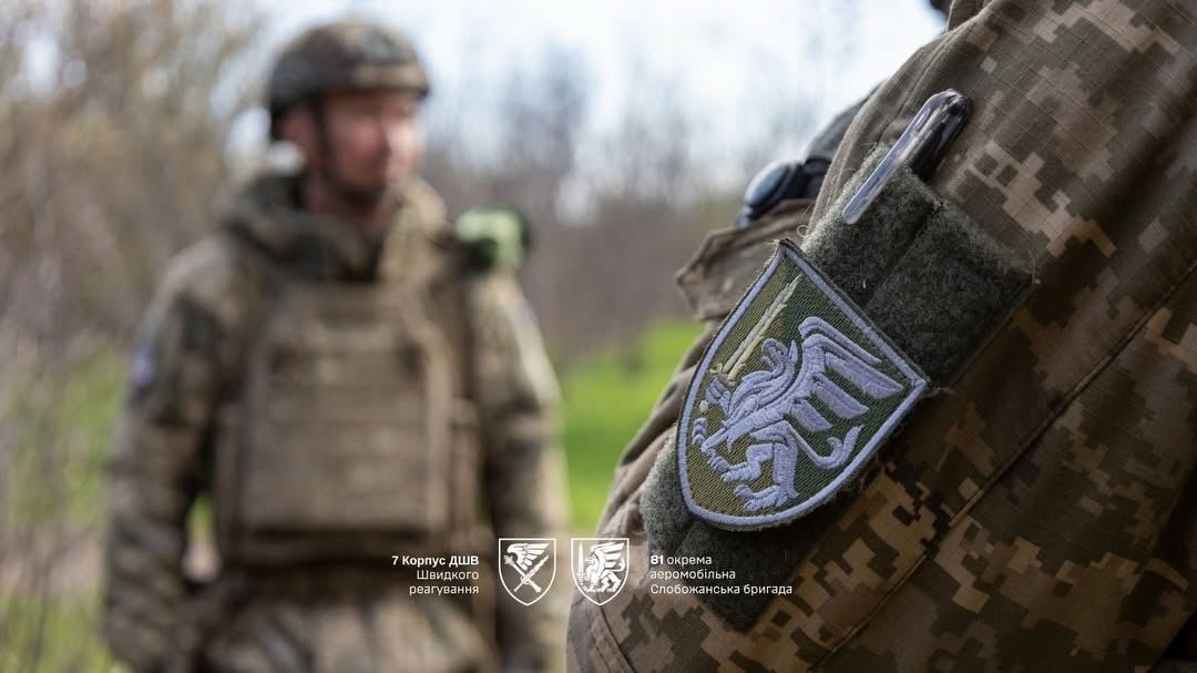 Шеврон 81-ї окремої аеромобільної Слобожанської бригади на формі військовослужбовця. На задньому плані розмито зображений інший боєць у захисному спорядженні.