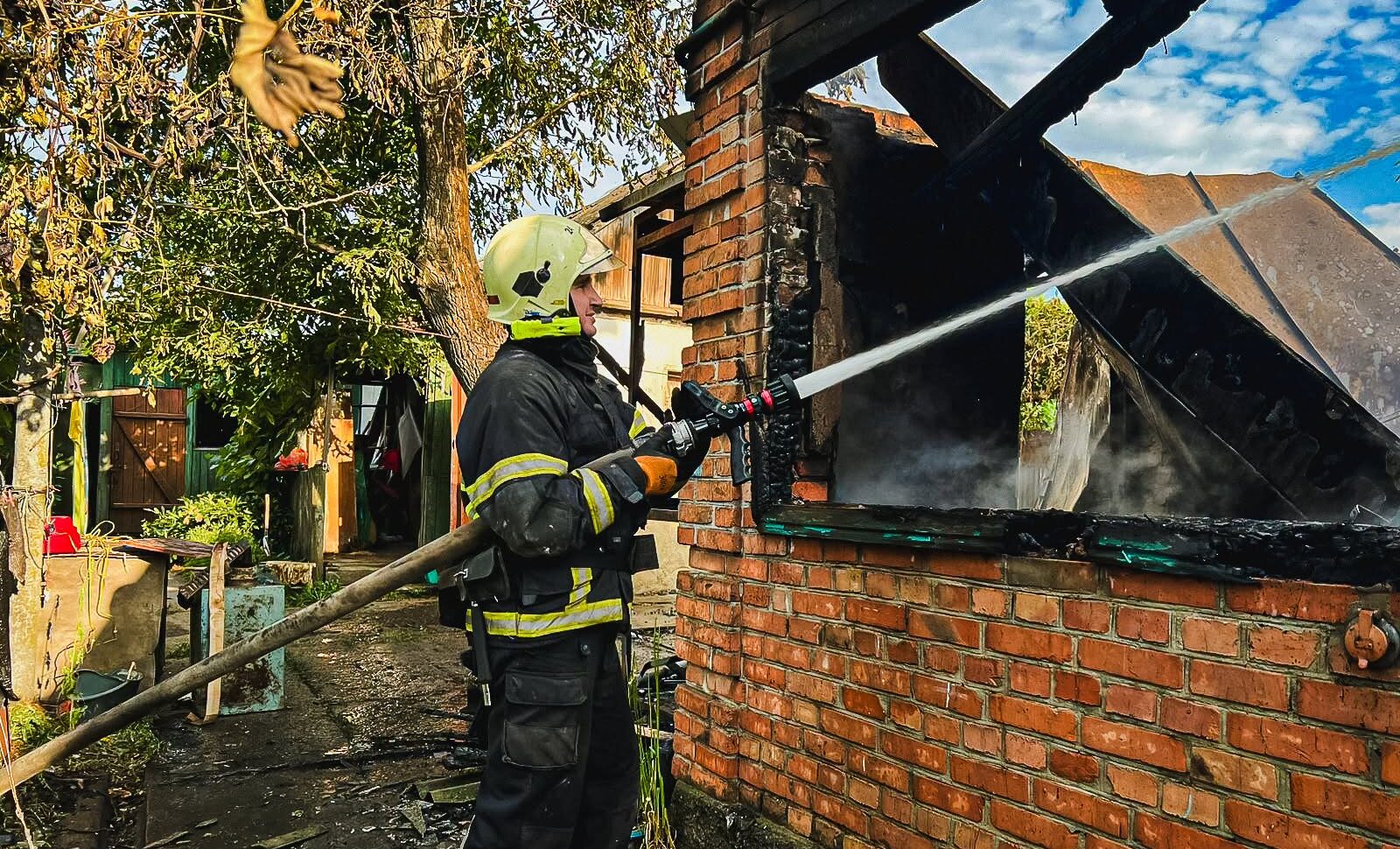 Рятувальник гасить пожежу у приватному будинку