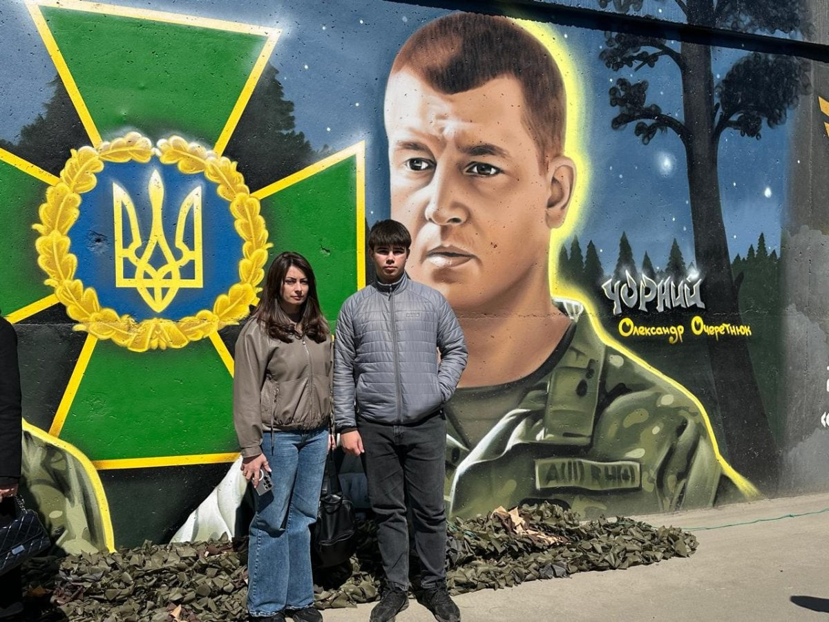 Дружина та син Олександра Очеретнюка поруч з муралом в його честь