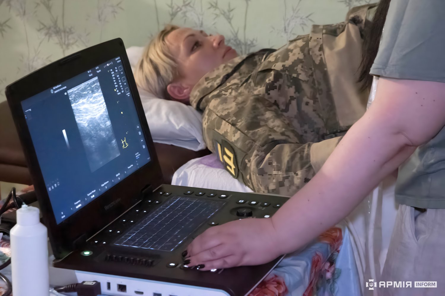 Лікар робить ультразвукову діагностику військовослужбовиці за допомогою мобільного апарата ультразвукової діагностики